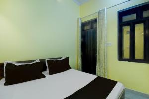 a bed with black pillows in a room with a window at Hotel O Krishna Palace in Jaipur