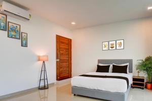 een witte slaapkamer met een bed en een houten deur bij Hotel O Lotus Inn in Chinchwad