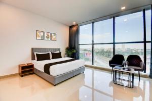 een slaapkamer met een bed en een stoel en grote ramen bij Hotel O Lotus Inn in Chinchwad