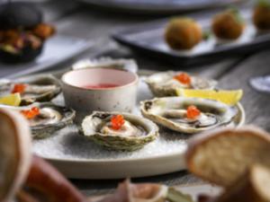 a plate of oysters with a bowl of dipping sauce at Fable Terrace Downs Resort by MGallery in Windwhistle
