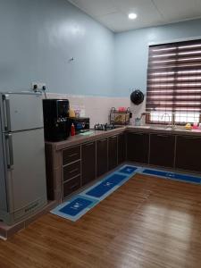 a kitchen with a refrigerator and a wooden floor at Adhwa Homestay in Kampong Bukit Katil