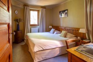 ein Schlafzimmer mit einem Bett und einem Tisch und einem Fenster in der Unterkunft Les Appartements du Mérilys in Méribel