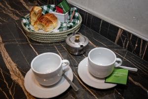 Twee kopjes en schotels op een tafel met een broodmandje. bij Apart Stay in El Calafate +22 foto's