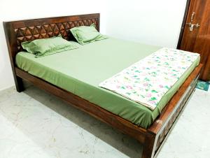 a bed with a wooden frame with a green mattress at Sakshi Seva Sadan Vrindavan Homestay & Restaurant in Vrindāvan