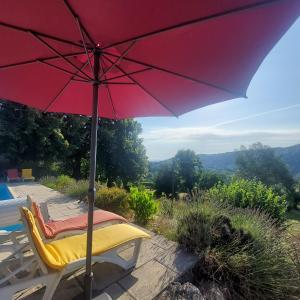 a red umbrella sitting on a chair next to a pool at Maison en pierre avec piscine in Ribes