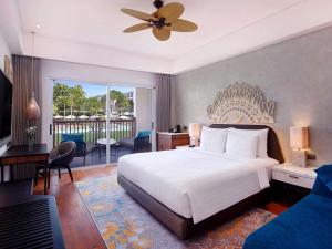 a bedroom with a large white bed and a balcony at Grand Mercure Bali Seminyak in Seminyak