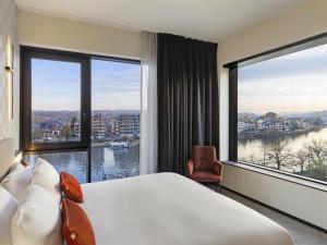 a hotel room with a large bed and large windows at Mercure Namur Hotel in Namur