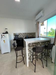 a kitchen with a counter with chairs and a refrigerator at WT Corais Flats in Maragogi