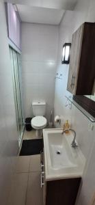 a white bathroom with a toilet and a sink at MM Apart Premium Joinville in Joinville