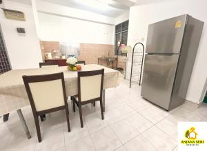 a kitchen and dining room with a table and a refrigerator at Cozy Stay ANJANA SERI GUEST HOUSE HOMESTAY Melaka in Ayer Keroh