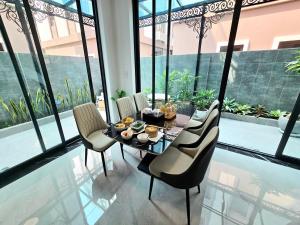a dining table and chairs in a room with windows at Aura Homestay in Cửu Cảo