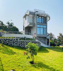 une maison au sommet d'un champ verdoyant avec un arbre dans l'établissement Ferns Citadel, à Karjat