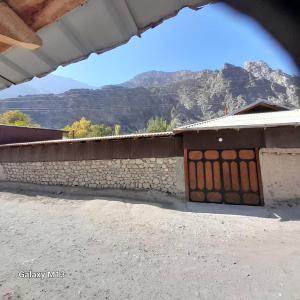 a building with a wall with a mountain in the background at Gasthaus Jasur,Yakkakhona 