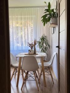 a dining room table with white chairs and a window at Feels like home in Visaginas