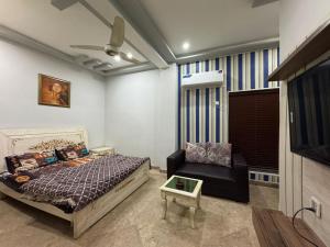 een slaapkamer met een bed, een stoel en een tv bij 1 bed apartment in Rawalpindi