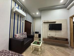 een woonkamer met een zwarte bank en een flatscreen-tv bij 1 bed apartment in Rawalpindi