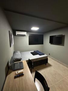 een kamer met een bed, een bureau en een tafel bij Apartmento aconchegante no centro da capital in Brasilia