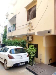 une voiture blanche garée devant un immeuble dans l'établissement Mifa, Appartement RDC de 2 chambres, pour famille, à Dakar 3 autres photos