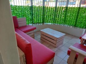 een afgeschermde veranda met rode meubels en groene planten bij Serene on 5 Cologne in Germiston