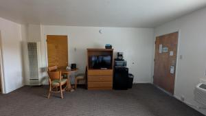 a room with a desk and a tv and a table at Himont Motel in Fall River Mills