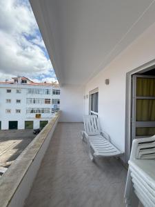 a balcony with two white chairs on a building at Casa Macedo in Vila Real de Santo António