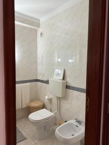 a bathroom with a white toilet and a sink at Casa Macedo in Vila Real de Santo António