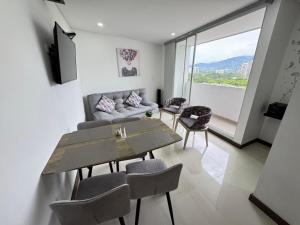 a living room with a couch and a table and chairs at Fundadores Apartment with balcony, pool, gym in Armenia