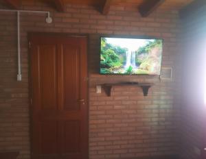 a television on a brick wall with a waterfall at La casa de Milac in Mina Clavero