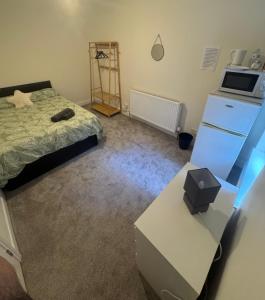 een slaapkamer met een bed, een dressoir en een bureau bij Quarto privativo em uma casa com outros quartos e banheiro compartilhado in Peterborough