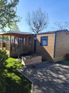 a wooden cabin with a porch and a deck at Super Mobil-Home Camping Les Sables Du Midi Valras-Plage in La Celle-sous-Gouzon