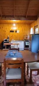 a kitchen with a wooden table and a table and chairs at Aves & árboles Casa 7p piscina y fogón in El Cerrillo