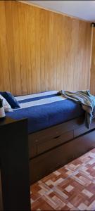 a bed with a blue blanket on top of it at Aves & árboles Casa 7p piscina y fogón in El Cerrillo