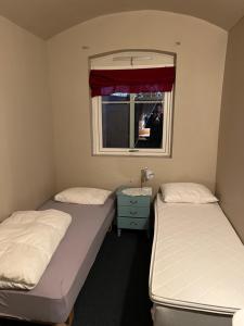 two beds in a small room with a window at Fengselet Gjestegård in Leira +15 photos
