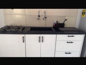 a kitchen with white cabinets and a stove top oven at Apache appartement in Paramaribo +4 photos