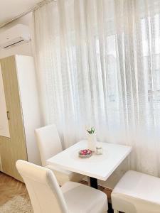 een witte tafel en stoelen in een kamer met een raam bij Gold Apartments in Novi Pazar