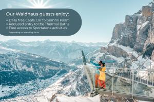 Una mujer parada en lo alto de una torre de vigilancia en las montañas. en Hotel Restaurant Waldhaus, en Leukerbad