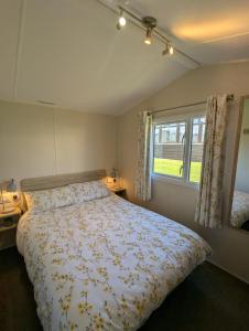 a bedroom with a large bed and a window at Modern Style Pet Friendly Holiday Home sited on Durdle Door Holiday Park in West Lulworth