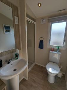 a bathroom with a sink and a toilet and a window at Modern Style Pet Friendly Holiday Home sited on Durdle Door Holiday Park in West Lulworth