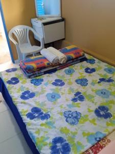 アウト・パライーゾ・デ・ゴイアスにあるQuarto privativo com banheiroの青い花が飾られたベッドと椅子