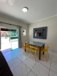 a dining room with a table and yellow chairs at Miragem de Bombinhas DUO in Bombinhas