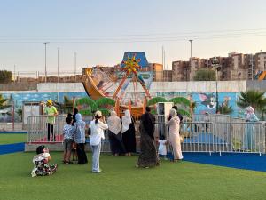a group of people standing in front of a carnival ride at Auberge Complexe Medina Parc in Mahelma
