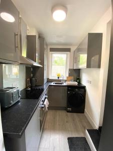 a kitchen with black counter tops and a sink at Thornton Road Lodge -Room 2 in Bradford