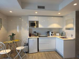 モハカルにあるSunrise Suiteの白いキャビネットとテーブルと椅子のあるキッチン