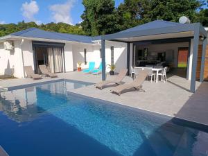 a pool with chairs and a table and a house at Villa 4 étoiles Bon Air in Bouillante