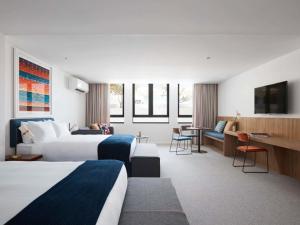 a hotel room with two beds and a desk at The Johnson Brisbane - Art Series in Brisbane