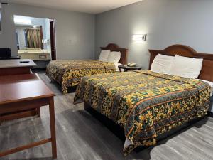 a hotel room with two beds and a desk at Claremore Motor Inn in Claremore