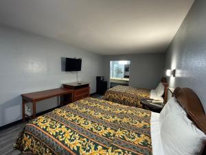 a hotel room with two beds and a flat screen tv at Claremore Motor Inn in Claremore +1 photo