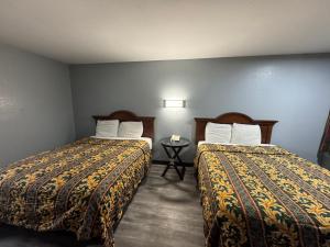 a hotel room with two beds and a table at Claremore Motor Inn in Claremore