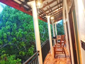 een veranda met 2 stoelen, een tafel en bomen bij SandaLuck House Ahangama in Ahangama