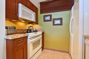 une cuisine avec des appareils électroménagers blancs et des armoires en bois dans l'établissement Mahana 1217 Oceanfront, à Lahaina